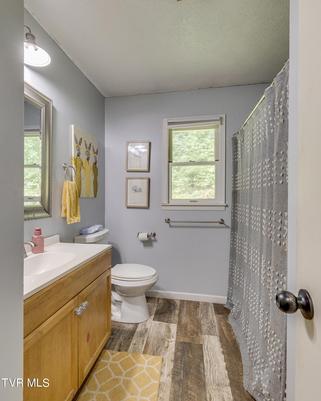 bathroom with wood-type flooring, a textured ceiling, toilet, a shower with curtain, and vanity