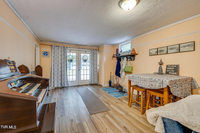 dining area featuring french doors, a textured ceiling, ornamental molding, and hardwood / wood-style floors