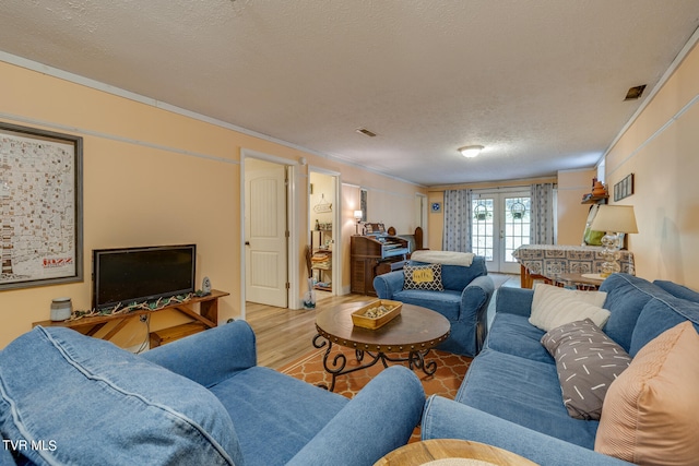 living room featuring ornamental molding, french doors, a textured ceiling, and hardwood / wood-style flooring