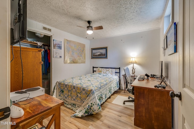 bedroom with light hardwood / wood-style floors, a closet, a textured ceiling, and ceiling fan