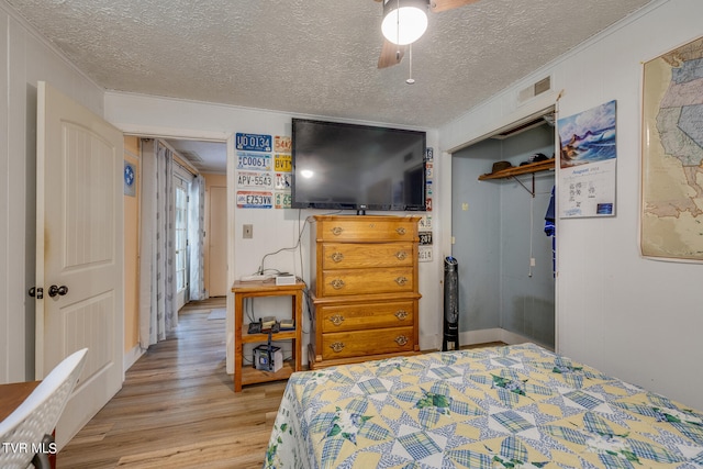 bedroom with crown molding, light hardwood / wood-style floors, a closet, and ceiling fan