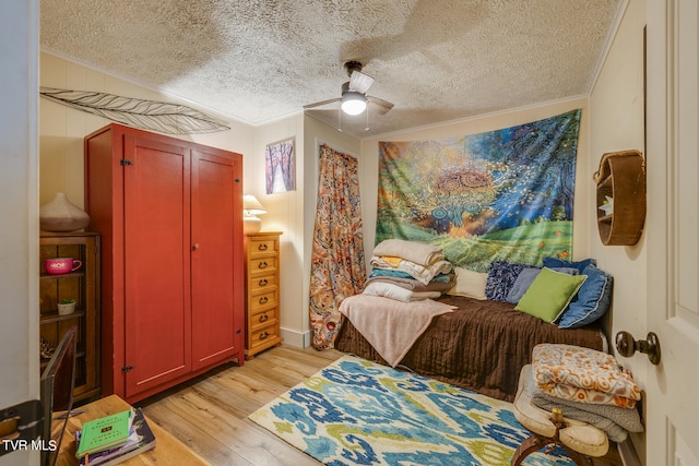 bedroom with ornamental molding, light hardwood / wood-style flooring, a textured ceiling, and ceiling fan