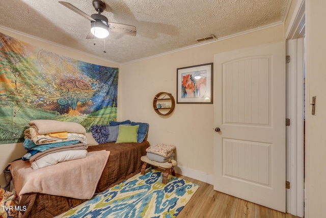 living area featuring crown molding, a textured ceiling, light wood-type flooring, and ceiling fan