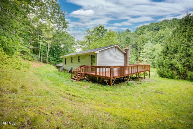 back of property featuring a wooden deck and a lawn