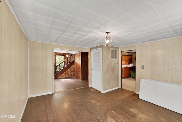 empty room featuring a notable chandelier and dark hardwood / wood-style flooring