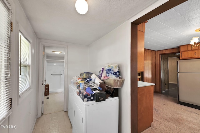 laundry room with wooden walls, washing machine and clothes dryer, and a textured ceiling