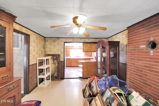 interior space with crown molding, ceiling fan, brick wall, and sink