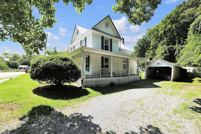 farmhouse with an outbuilding, a porch, a garage, and a front lawn