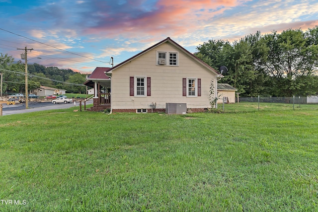 view of front of home featuring cooling unit and a yard