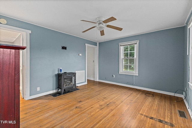 living room with a wood stove, hardwood / wood-style floors, and ceiling fan