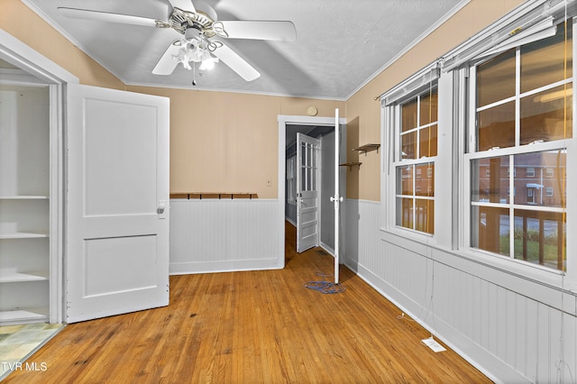 interior space with ceiling fan, light wood-type flooring, ornamental molding, and a textured ceiling