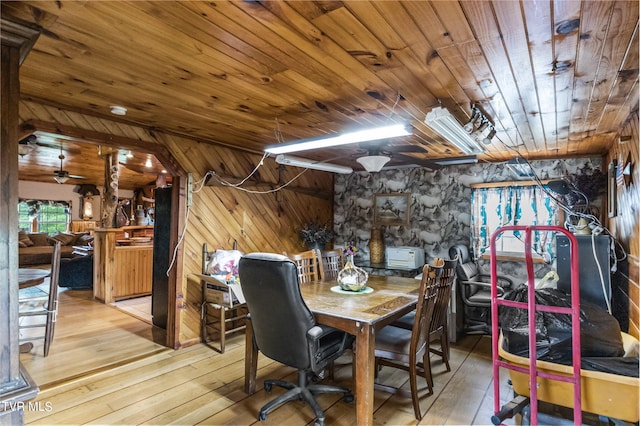 dining space with light hardwood / wood-style flooring, wood walls, and wood ceiling