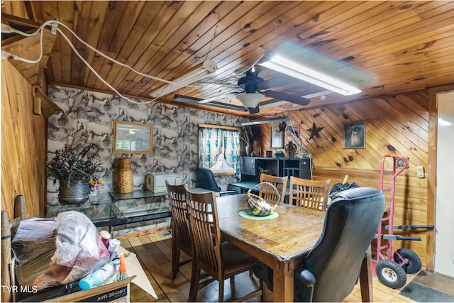 dining space featuring wooden ceiling, ceiling fan, wood walls, and light hardwood / wood-style flooring