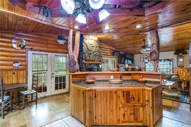 kitchen featuring lofted ceiling, wooden ceiling, ceiling fan, light hardwood / wood-style floors, and rustic walls