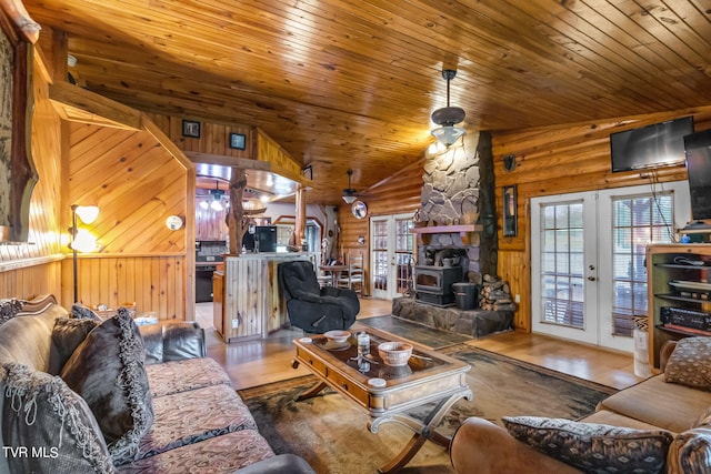 living room with french doors, lofted ceiling, a wood stove, hardwood / wood-style floors, and wood ceiling