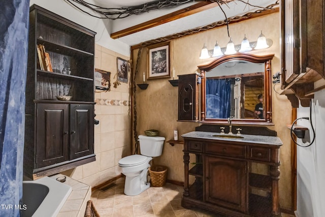 bathroom featuring toilet, tile walls, tile patterned floors, a tub to relax in, and vanity