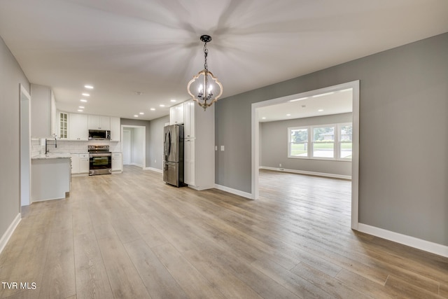 unfurnished living room with sink, light hardwood / wood-style flooring, and a chandelier