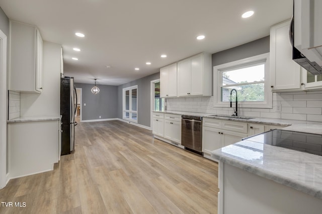 kitchen featuring decorative backsplash, light hardwood / wood-style flooring, light stone counters, appliances with stainless steel finishes, and sink