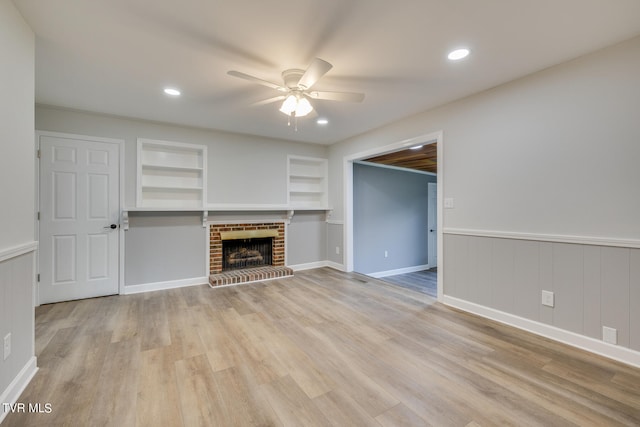 unfurnished living room featuring a brick fireplace, light hardwood / wood-style flooring, and built in features