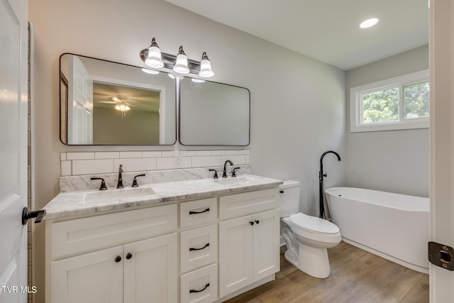 bathroom with double sink vanity, toilet, hardwood / wood-style floors, and backsplash