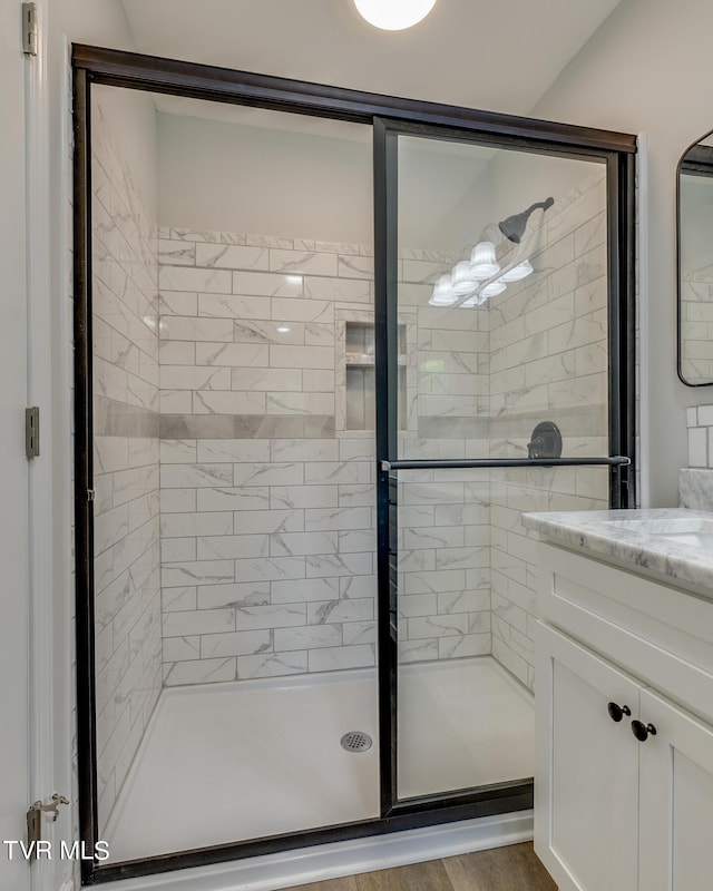 bathroom with a shower with shower door, wood-type flooring, and vanity