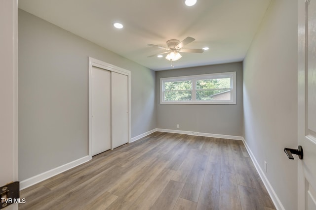 unfurnished bedroom featuring ceiling fan, a closet, and wood-type flooring