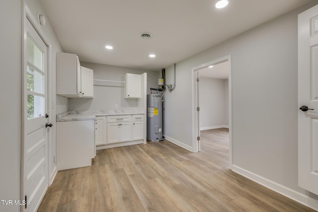 kitchen with electric water heater, light hardwood / wood-style flooring, and white cabinets