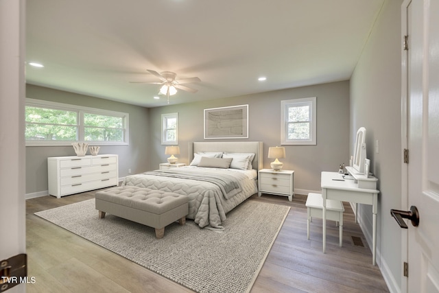 bedroom with ceiling fan, wood-type flooring, and multiple windows