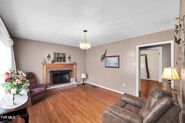 living room with wood-type flooring, a fireplace, and a chandelier