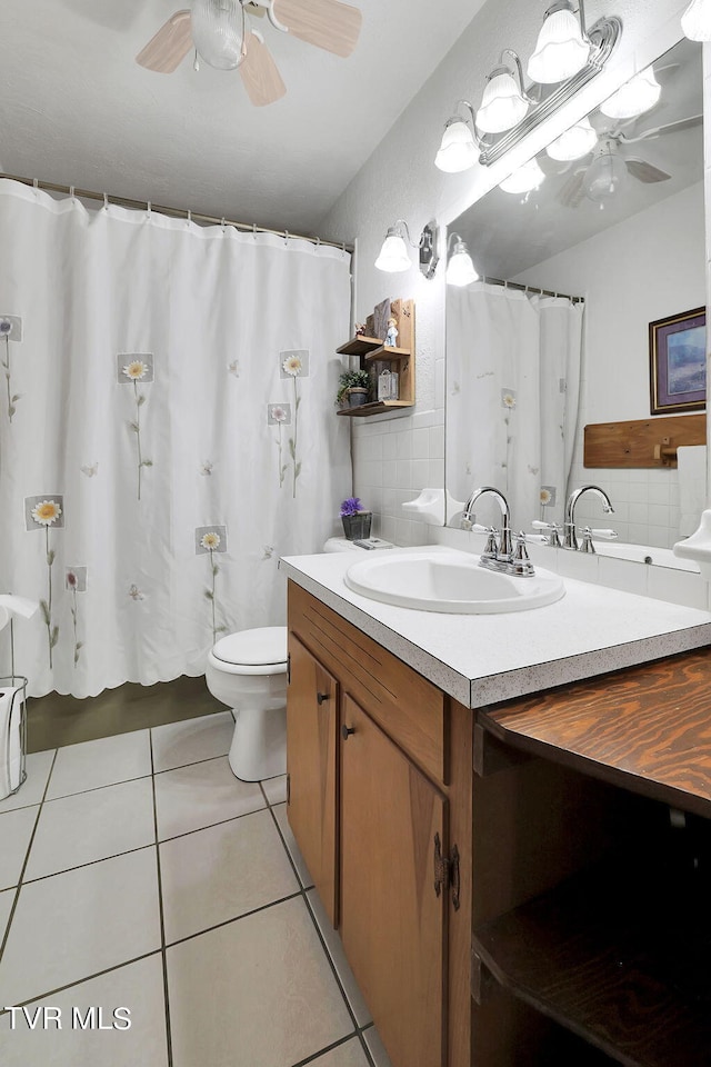 bathroom with tile patterned flooring, walk in shower, toilet, ceiling fan, and vanity