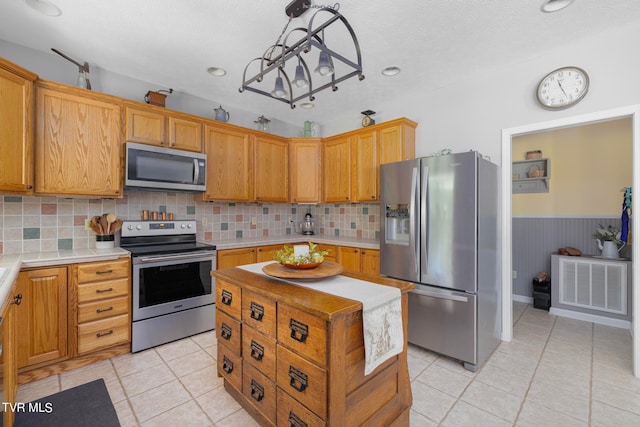 kitchen with decorative backsplash, light tile patterned floors, and stainless steel appliances