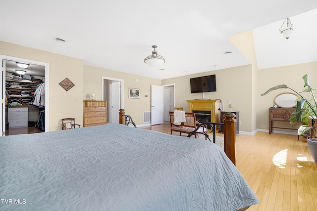 bedroom with a closet, light hardwood / wood-style flooring, and a walk in closet