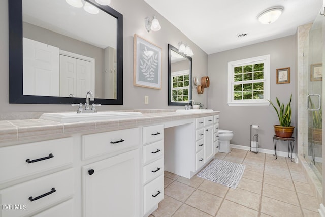 bathroom featuring dual vanity, a shower with door, toilet, and tile patterned flooring