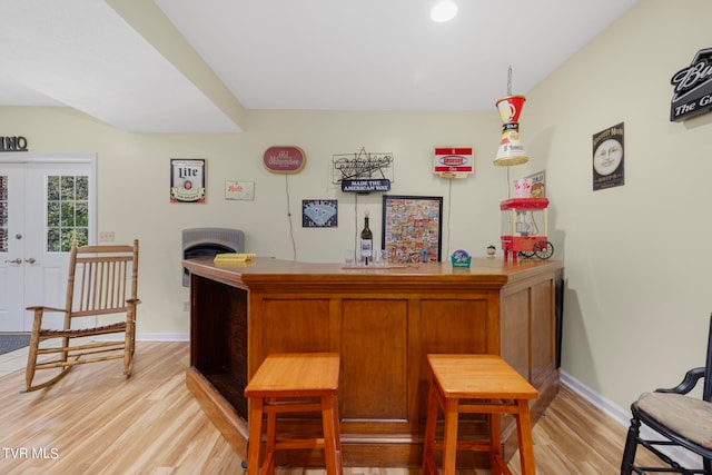 bar with light hardwood / wood-style flooring, french doors, and decorative light fixtures