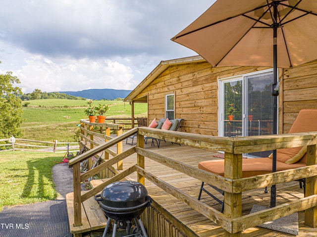 wooden terrace featuring fence, area for grilling, a rural view, a lawn, and a mountain view