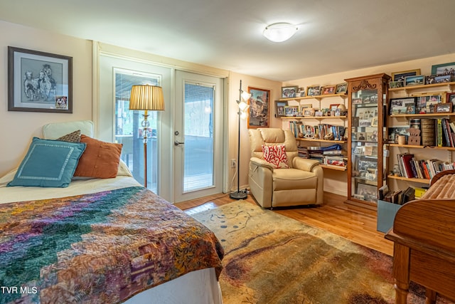 bedroom with access to outside and wood finished floors