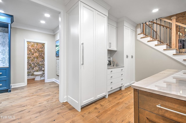 interior space with crown molding, light hardwood / wood-style floors, and white cabinets