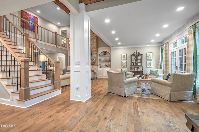 living room with french doors, built in shelves, light wood-type flooring, ornamental molding, and decorative columns