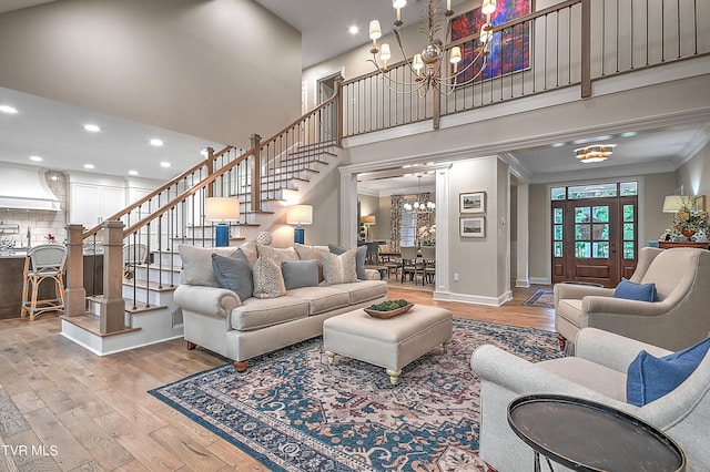 living room with a notable chandelier, crown molding, a towering ceiling, and hardwood / wood-style flooring