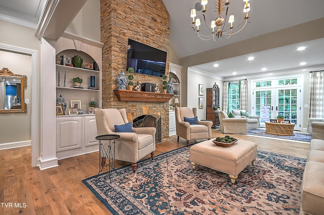 living room featuring ornamental molding, a stone fireplace, a chandelier, and light hardwood / wood-style floors