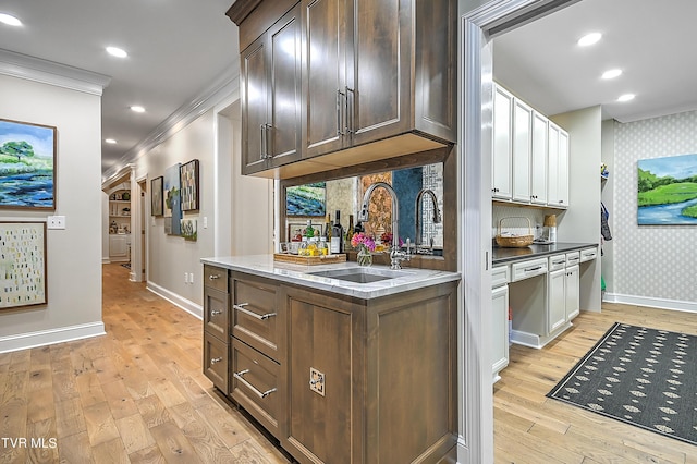 kitchen featuring sink, tasteful backsplash, dark brown cabinets, light hardwood / wood-style flooring, and ornamental molding