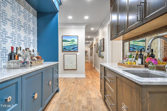 bar featuring crown molding, sink, light stone counters, and light wood-type flooring