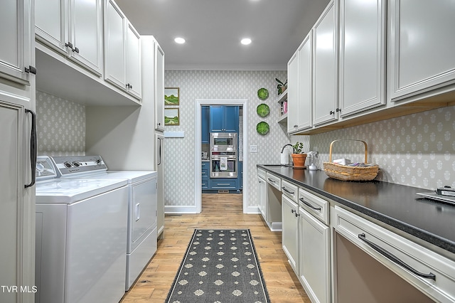 washroom with sink, washing machine and dryer, cabinets, and light wood-type flooring