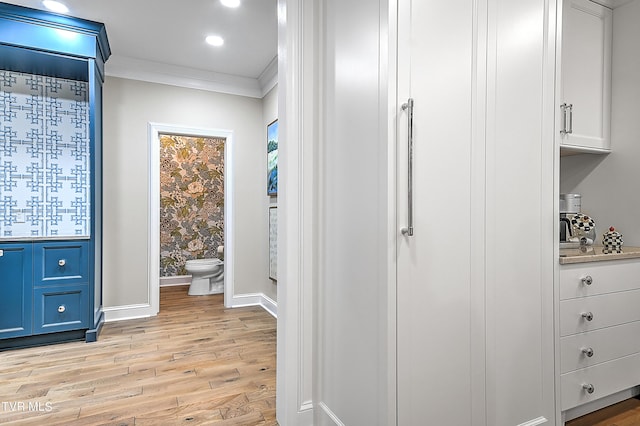 interior space featuring hardwood / wood-style flooring, ornamental molding, and toilet