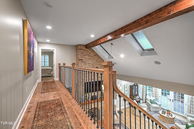 hall featuring hardwood / wood-style flooring, a wealth of natural light, and vaulted ceiling with skylight