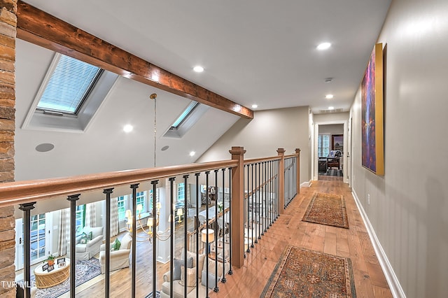 corridor with vaulted ceiling with skylight and light hardwood / wood-style flooring