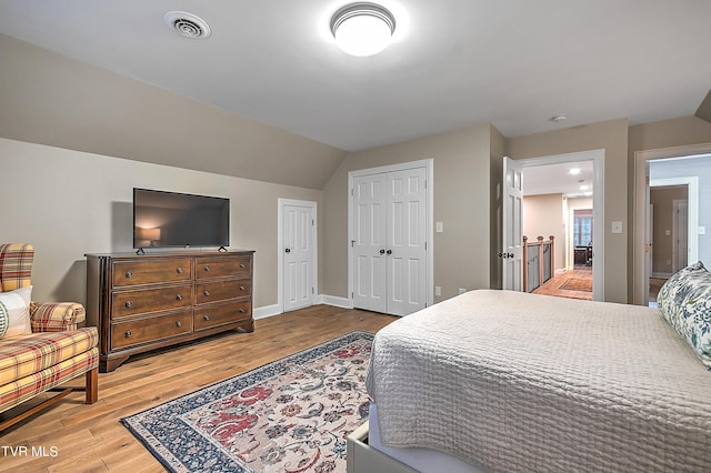 bedroom with vaulted ceiling, light hardwood / wood-style floors, and a closet