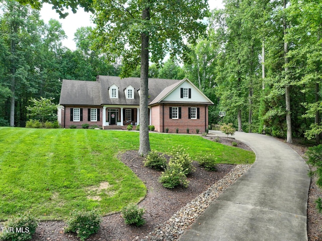 new england style home with a front yard and covered porch