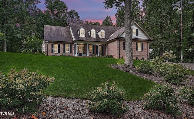 cape cod house with covered porch and a lawn