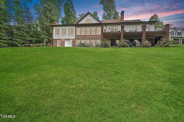 back house at dusk with a wooden deck and a yard